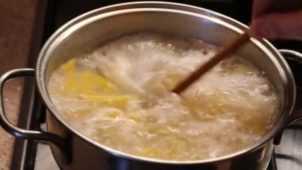 用木勺把意大利面放在锅里的开水里搅拌 — 图库视频影像