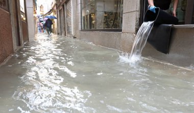 Venedik 'teki selden ve deniz suyuyla kaplı dar sokaktan sonra dükkanın içini boşaltan kişi.
