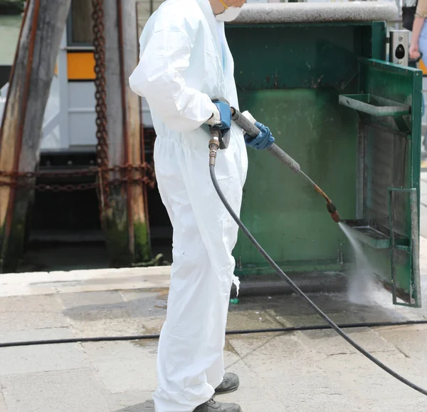 Worker during the disinfection with the jet of the pressure washer of the trash bin during the quarantine by Corona Virus in the European City