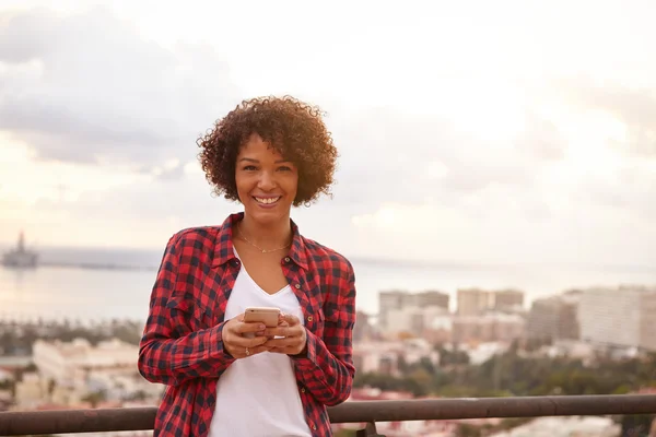 Girl with phone smiling at camera — Stock Photo, Image