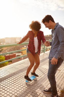 Erkek kıza kaykay binmek için yardım 