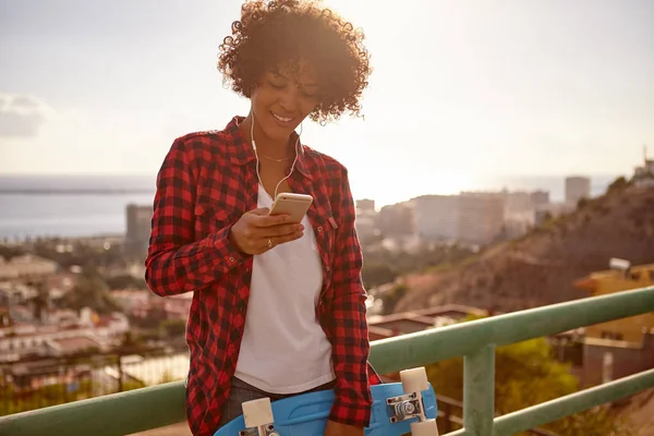 Smiling girl with skateboard and cellphone — Stock Photo, Image