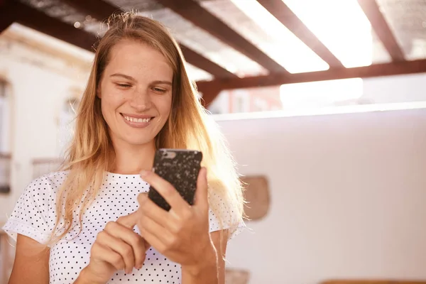 Chica rubia sonriente usando el teléfono celular — Foto de Stock