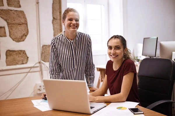 Unga kvinnor sitter vid skrivbord med laptop — Stockfoto
