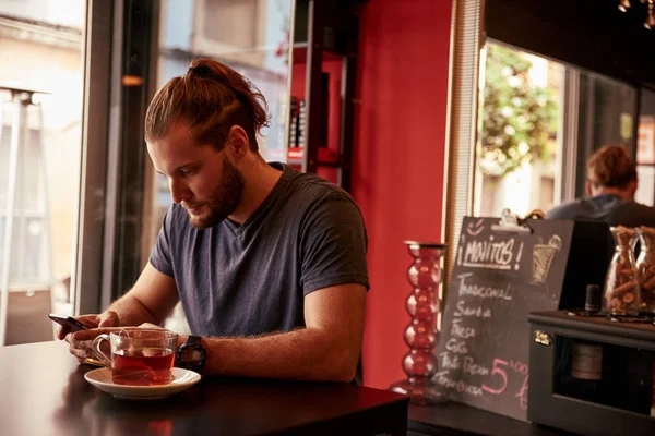 Genç adam akıllı telefon kullanıyor.