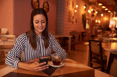 Akıllı telefon kullanan genç bir kadın.