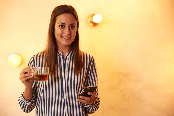 Kvinde med kop te og smartphone - Stock-foto