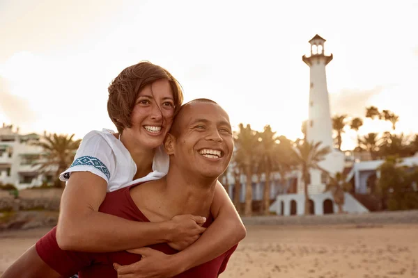 Coppia piggy back equitazione sulla spiaggia — Foto Stock