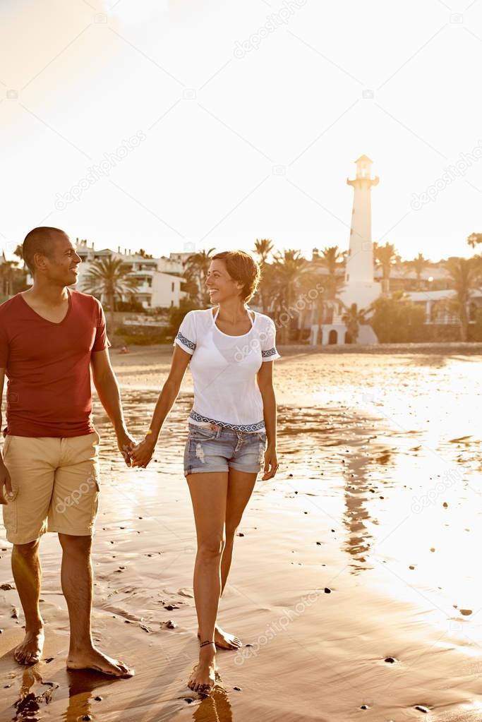 Loving couple walking barefoot on beach