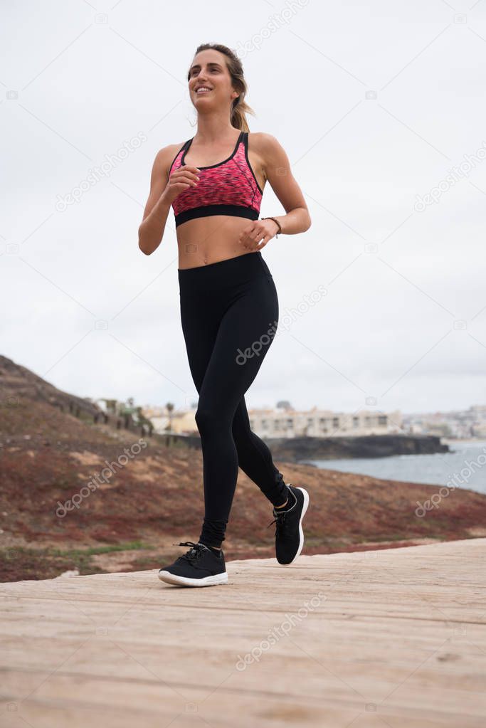Young pretty woman jogging on boarwalk