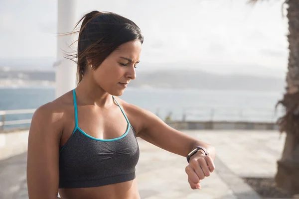 Young pretty brunette looking at smartwatch — Stock Photo, Image