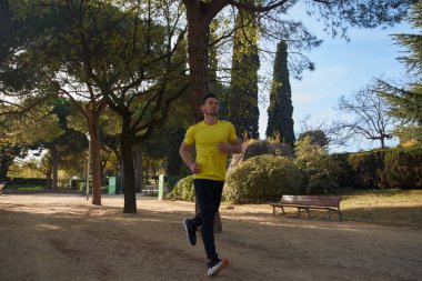 Genç adam parkta koşuyor.