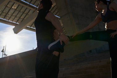 Genç çift birlikte bacak esnetiyorlar.