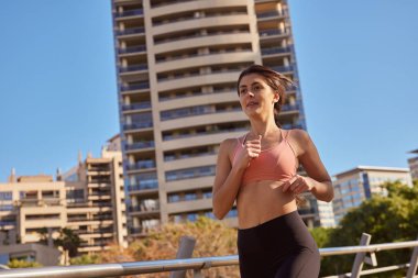 Kadın uzun bir binanın önünden geçiyor.