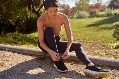 Bir kadın oturuyor ve bağcıklarını bağlıyor.