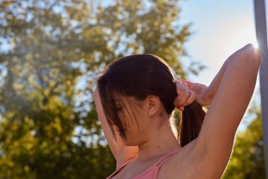 Kadın saçını midilli kuyruğuna çekiyor.