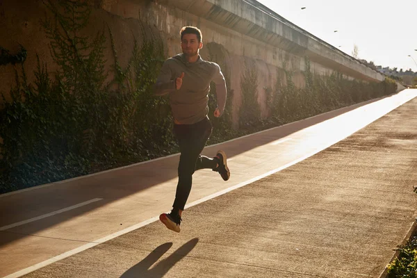 Hombre en equipo atlético corriendo por un camino — Foto de Stock