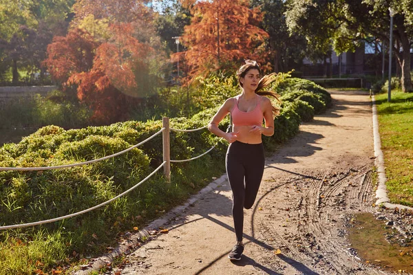 Žena jogging podél cesty v parku — Stock fotografie