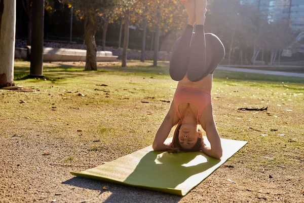 Young woman does a supported half head stand