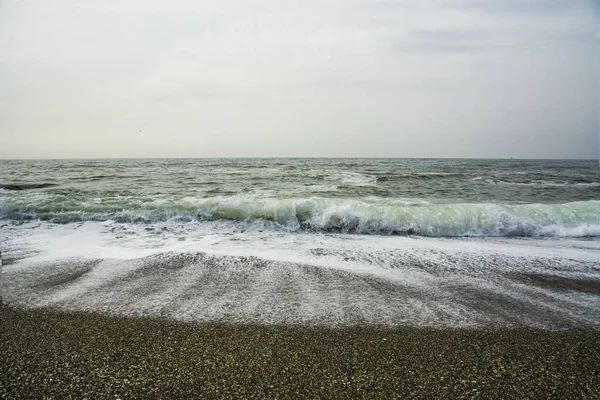 Gyönyörű kihalt strand, a hullámok és a bryzni, a sziklák, sima üveg — Stock Fotó