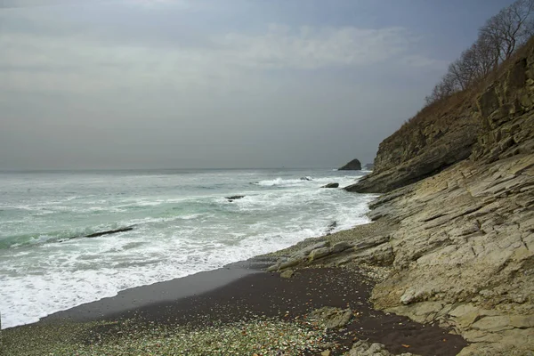 Bela praia deserta, ondas e bryzni nas rochas, vidro liso — Fotografia de Stock