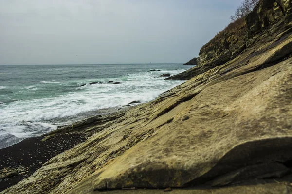 Hermosa playa desierta, olas y bryzni en las rocas, vidrio liso — Foto de Stock