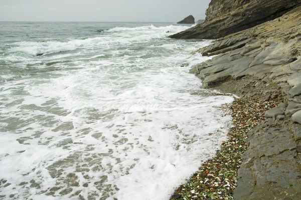 Hermosa playa desierta, olas y bryzni en las rocas, vidrio liso — Foto de Stock