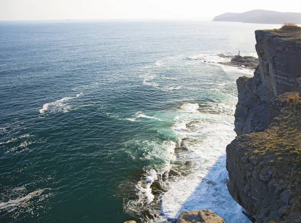 Penhasco alto acima do mar, o penhasco desce para o mar, muitas ondas salpicando e pedras — Fotografia de Stock