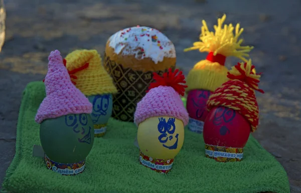 Easter eggs in caps, with funny faces in nature — Stock Photo, Image