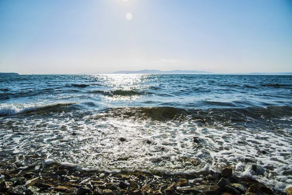 O sol se põe para o mar, as ondas na costa em manchas ensolaradas — Fotografia de Stock