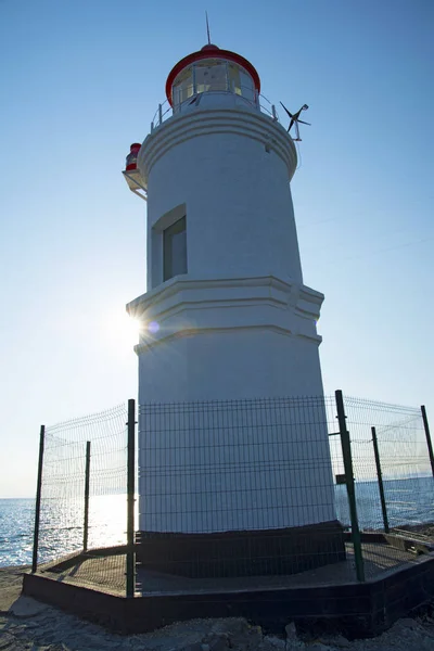 Um farol fica em uma plataforma elevada no meio do mar — Fotografia de Stock