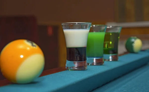 Num suporte de mesa de bilhar com copos coloridos de álcool . — Fotografia de Stock