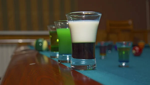 Op een biljart tafelstandaard met gekleurde glazen alcohol. — Stockfoto