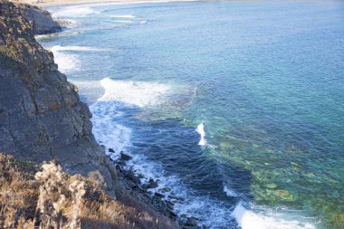 Güçlü kaya, görkemli kayalar ile güneş parlamayı, mavi bir denizde daraltır