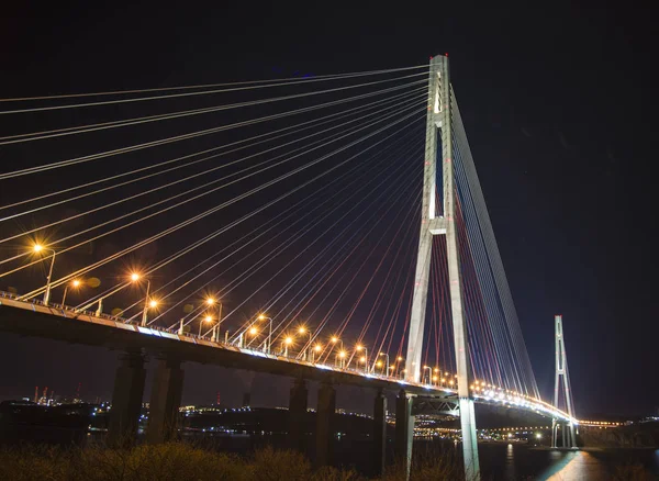 Belles lumières de la ville nocturne. pont élevé à travers la baie tendu sur des pylônes . — Photo
