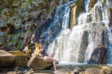 yüksek bir şelale içinde bir şelale kesinlikle ıssız Kızıl saçlı kız poz güzel kız.