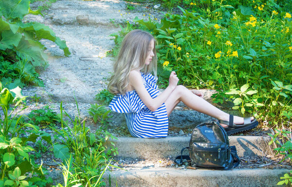 young beautiful girl sitting on the stairs in the park with flower, 
