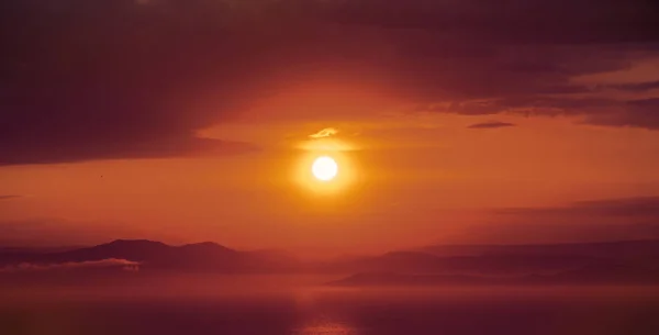 Um pôr do sol vermelho brilhante sobre o mar, depois da tempestade. Pôr do sol escarlate sobre a água e muitas nuvens . — Fotografia de Stock