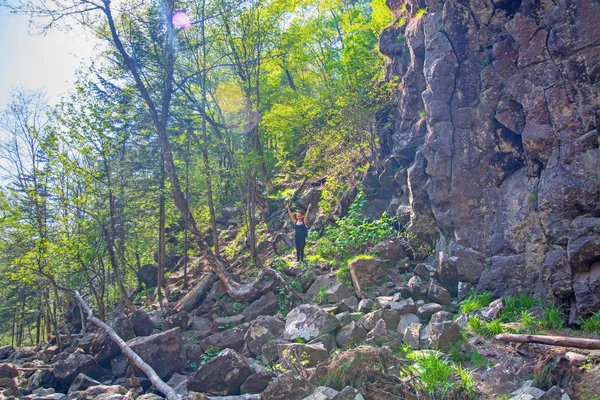 A lány gyönyörű erdős cliff, sok zöld növényzet és sziklák keresztül emelkedik. — Stock Fotó