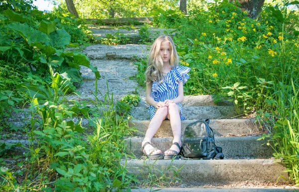 Krásná mladá dívka sedí na schodech v parku s květinou, — Stock fotografie