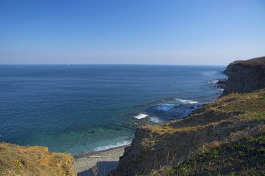 Güçlü kaya, görkemli kayalar ile güneş parlamayı, mavi bir denizde daraltır