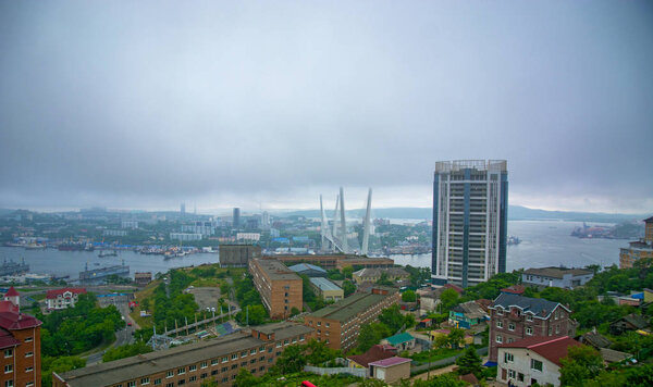 вид на город с высоты, высокий мост через залив, густой туман. Морской город

