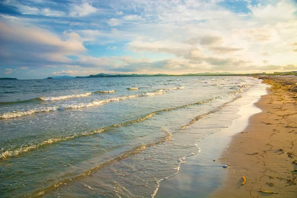 parlak altın günbatımı sahilde, kum, dalgalar kabuklar.