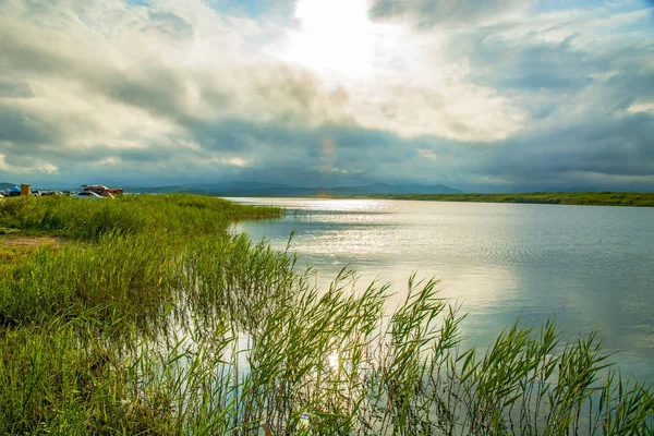 Lago claro con plantas verdes, densas nubes oscuras , — Foto de Stock