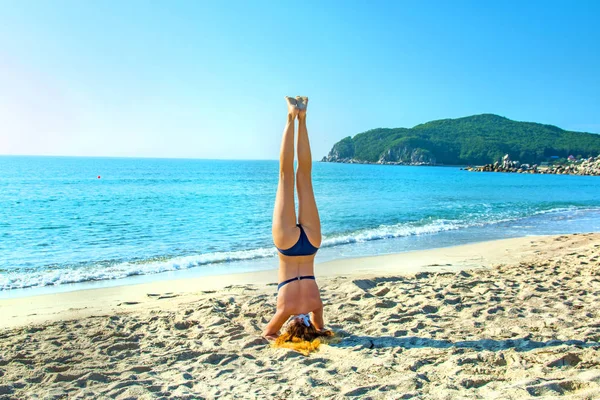 Jeune, belle, rousse fille pratique le yoga sur la plage . — Photo