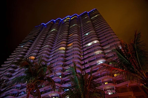Tall skyscrapers and beautiful palms, night city in the tropics, the combination of nature and architecture. — Stock Photo, Image