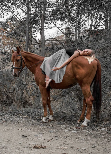 Mladé krásné tanečnice, pózuje s koněm v lese, pružná gymnastka. — Stock fotografie