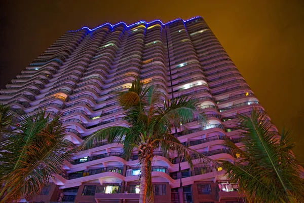 tall skyscrapers and beautiful palms, night city in the tropics, the combination of nature and architecture. Asia
