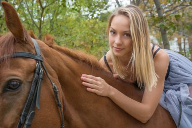Genç sarışın kız bir at, güzel bir kız ve güçlü bir at ile poz.