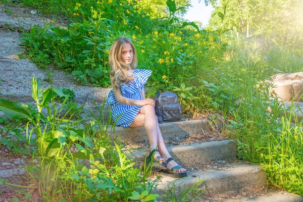 Jovem menina bonita sentada nas escadas do parque com flor , — Fotografia de Stock